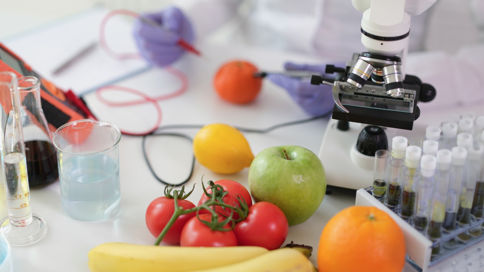 A microscope, test tubes and fruit on a white table