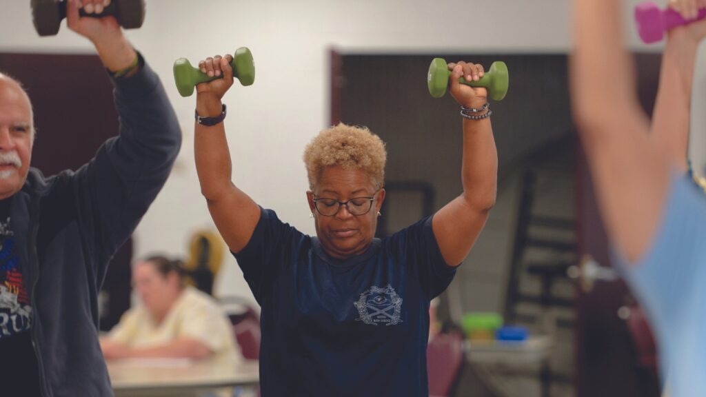 woman with short hair lifting two dumbbells 