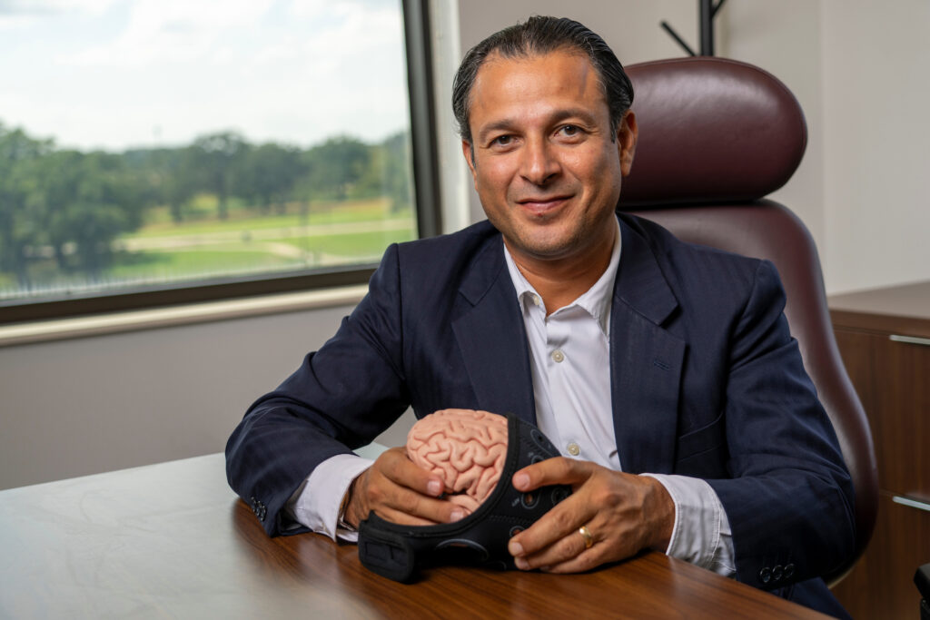 Marco Palma is seated at his desk, holding a model of the human brain which indicates his study of human psychology and behavior