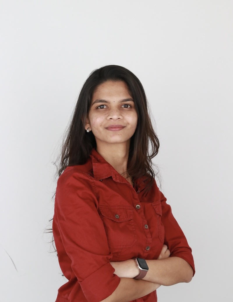 Woman with dark hair wears a red button down and smiles at camera